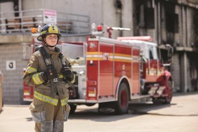 火 Academy student with fire-fighting equipment and uniform standing in front of a fire truck